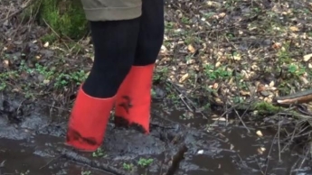 Mit roten Absatz-Gummistiefeln hilflos im Sumpf stecken geblieben